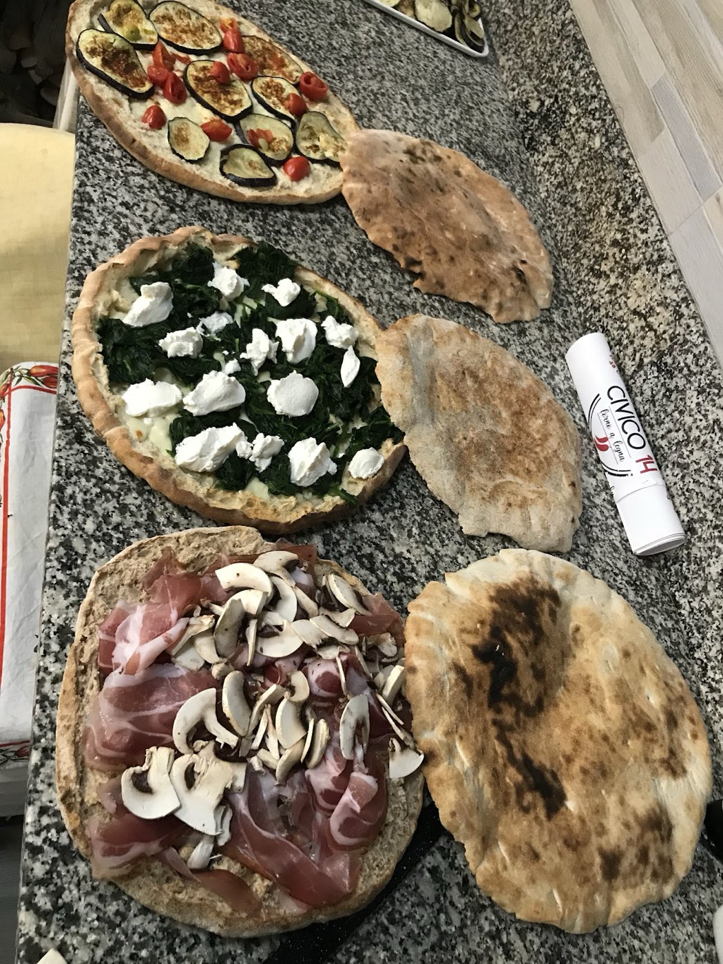 Pizze e pane profumato appena usciti dal forno a legna, sul bancone di granito