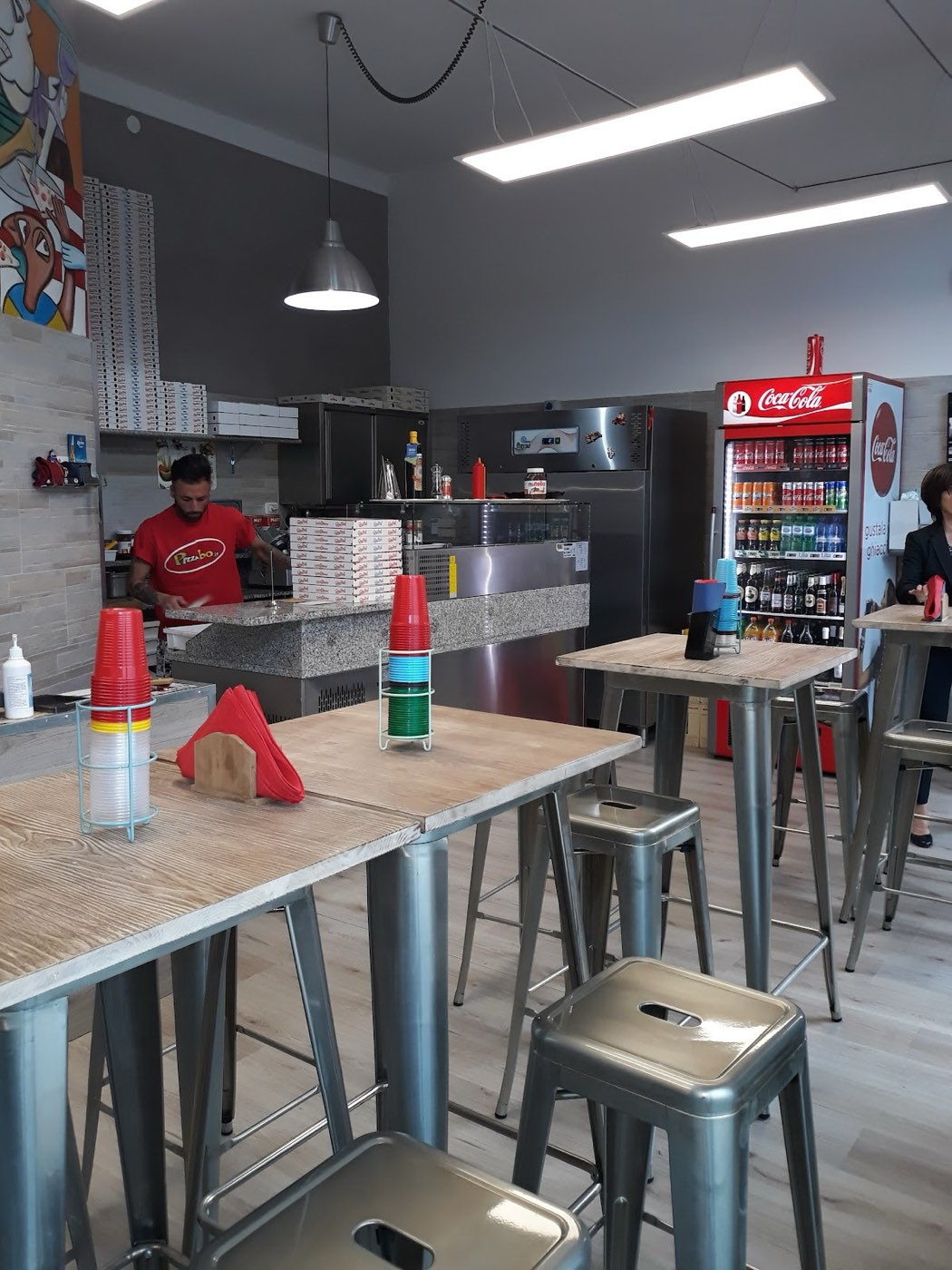 La sala della pizzeria, con il bancone e i tavoli alti